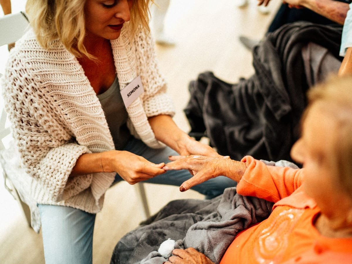 A caregiver assisting a senior woman sitting comfortably at home