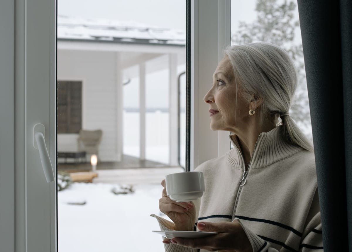 An older woman holding a cup of coffee at home